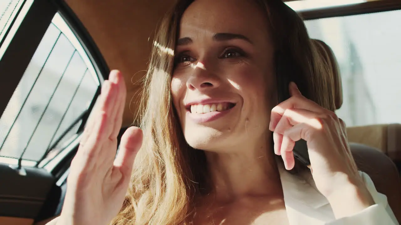 Happy businesswoman surprising to hear good news on phone in business car