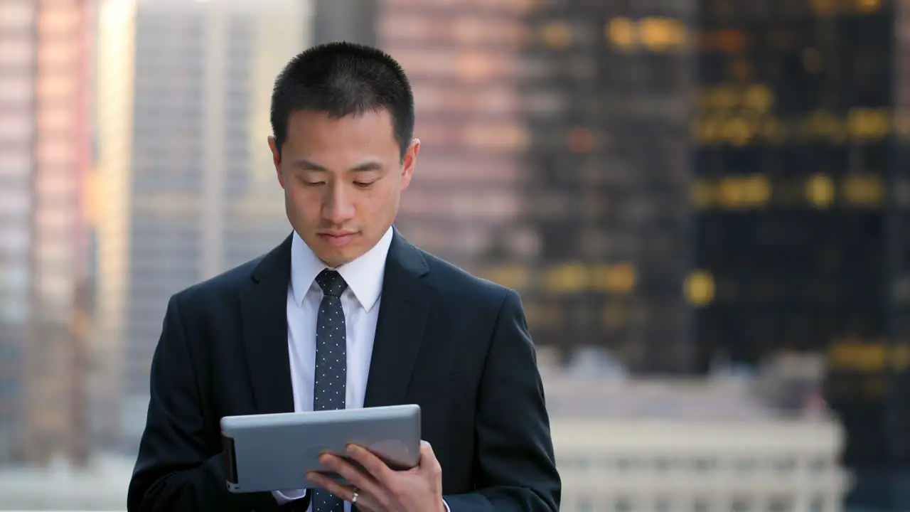 Front view of young Asian Businessman working on digital tablet i4k