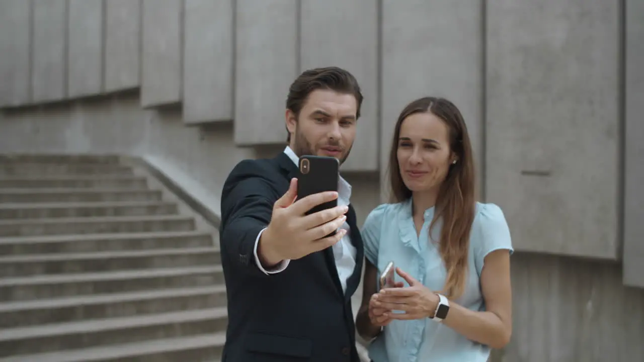 Successful coworkers using cellphone for video call on urban street