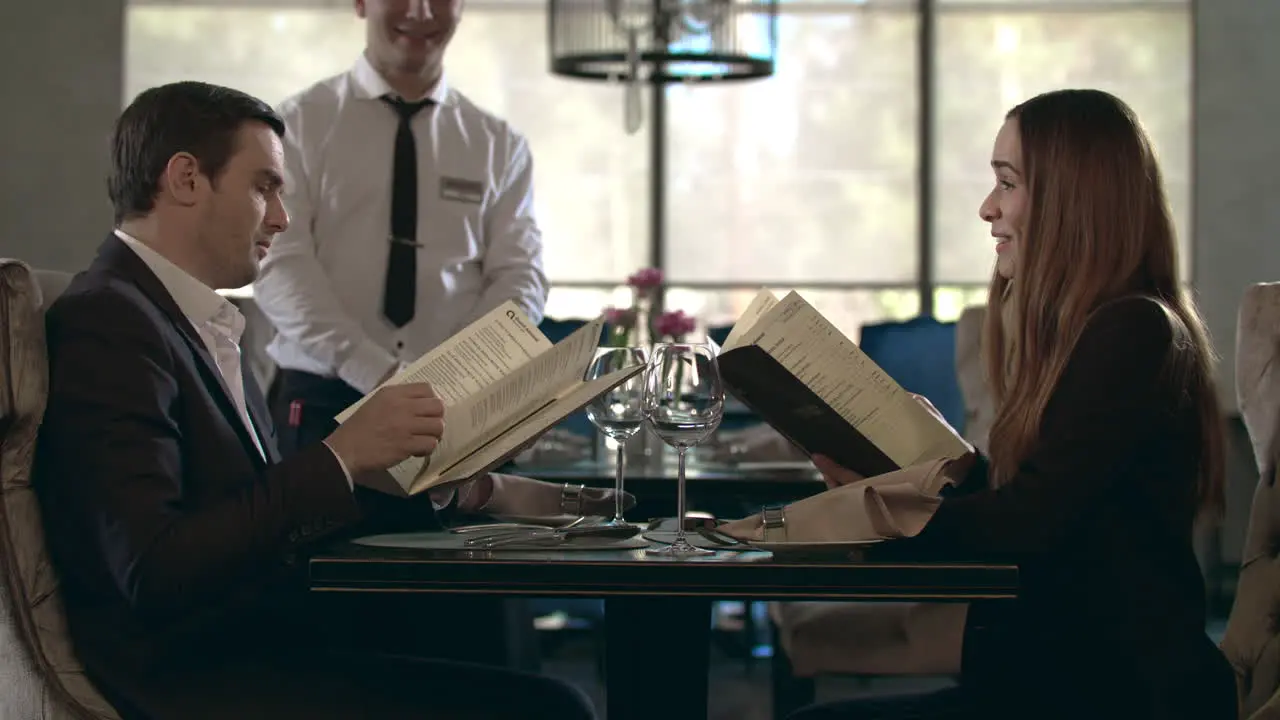 Happy couple reading menu in restaurant Business people choosing food in cafe