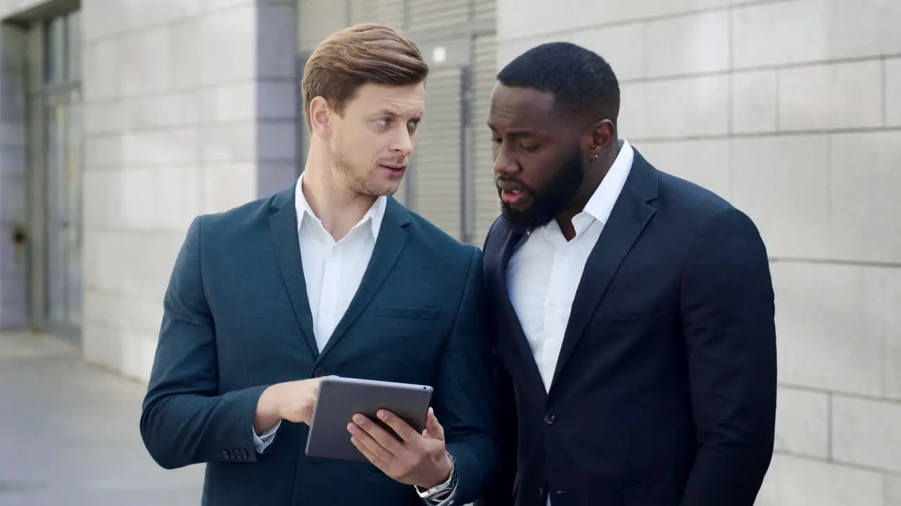 Businessmen working on tablet in city Business men using touchpad outside