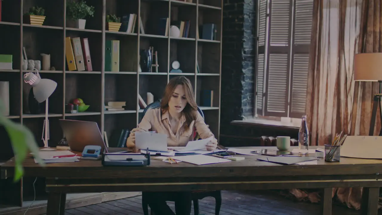 Attractive business woman reading graphics on documents at workplace