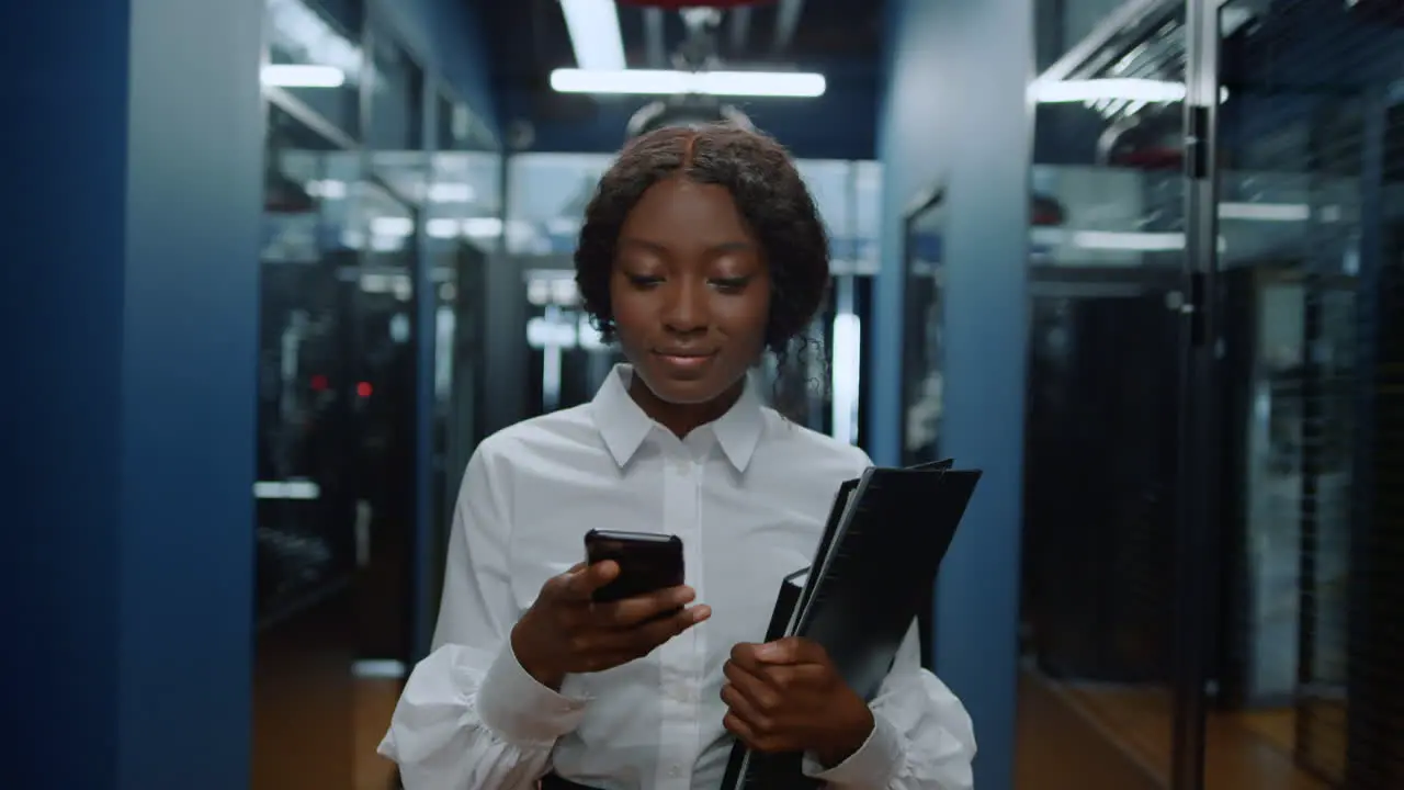 Afro woman having phone conversation in corridor African lady texting in office