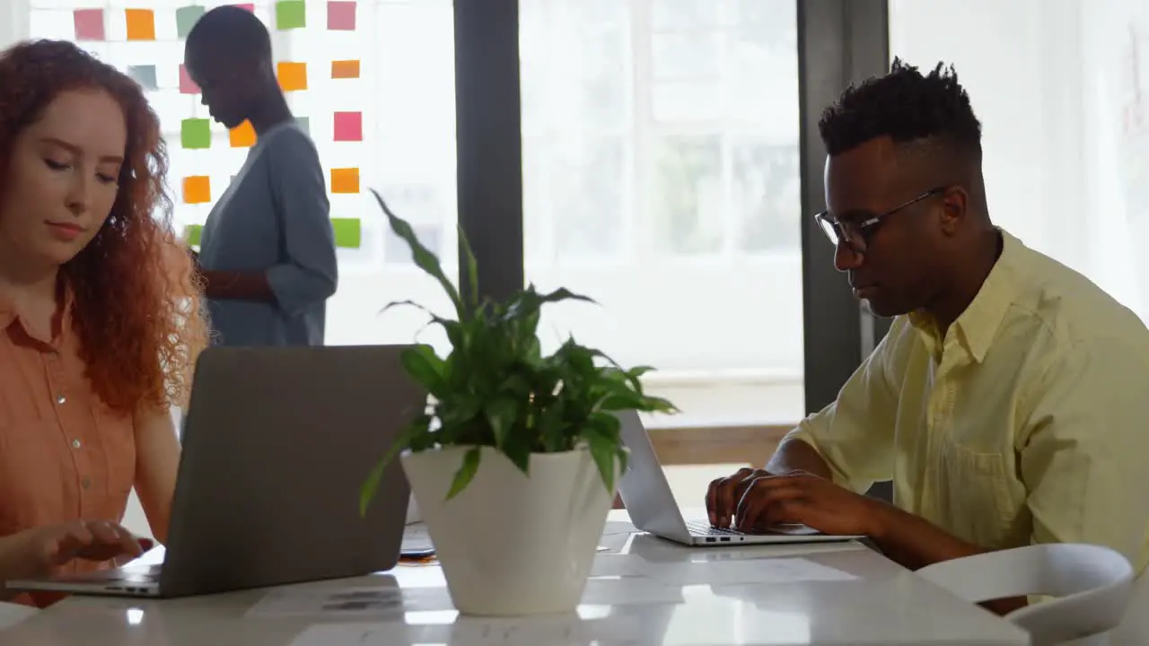 Side view of young mixed-race business team sitting at table and working in a modern office 4k