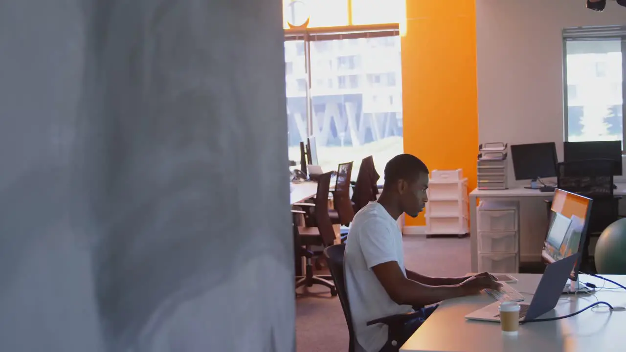 Side view of young black male executive working on computer at desk in modern office 4k