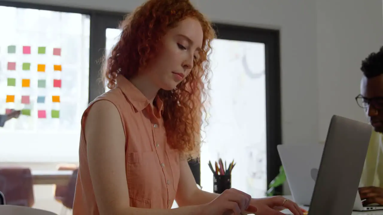 Side view of young caucasian businesswoman working on laptop in a modern office 4k