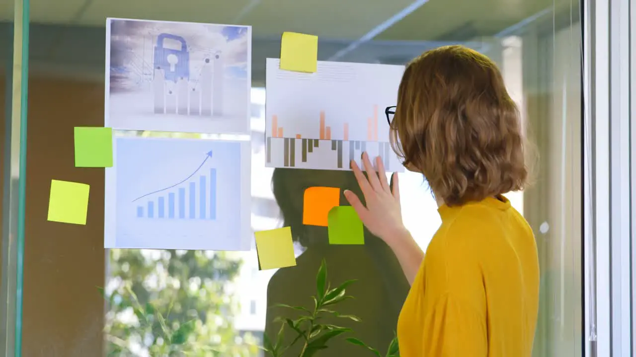 Rear view of businesswoman looking at graphs in modern office 4k