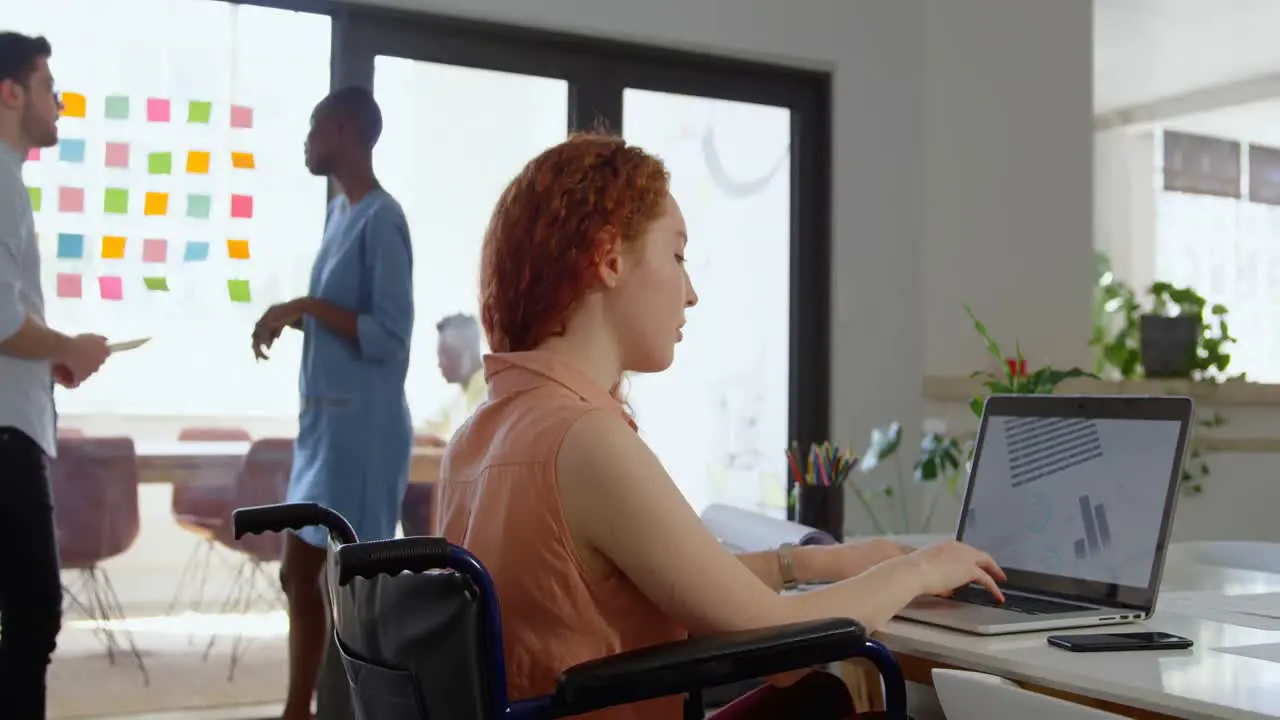 Side view of disable young caucasian businesswoman working on laptop in a modern office 4k