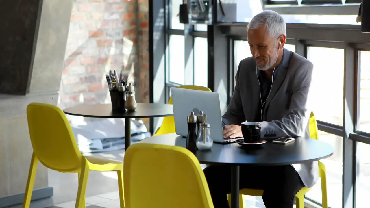 Businessman having coffee while using laptop in hotel 4k