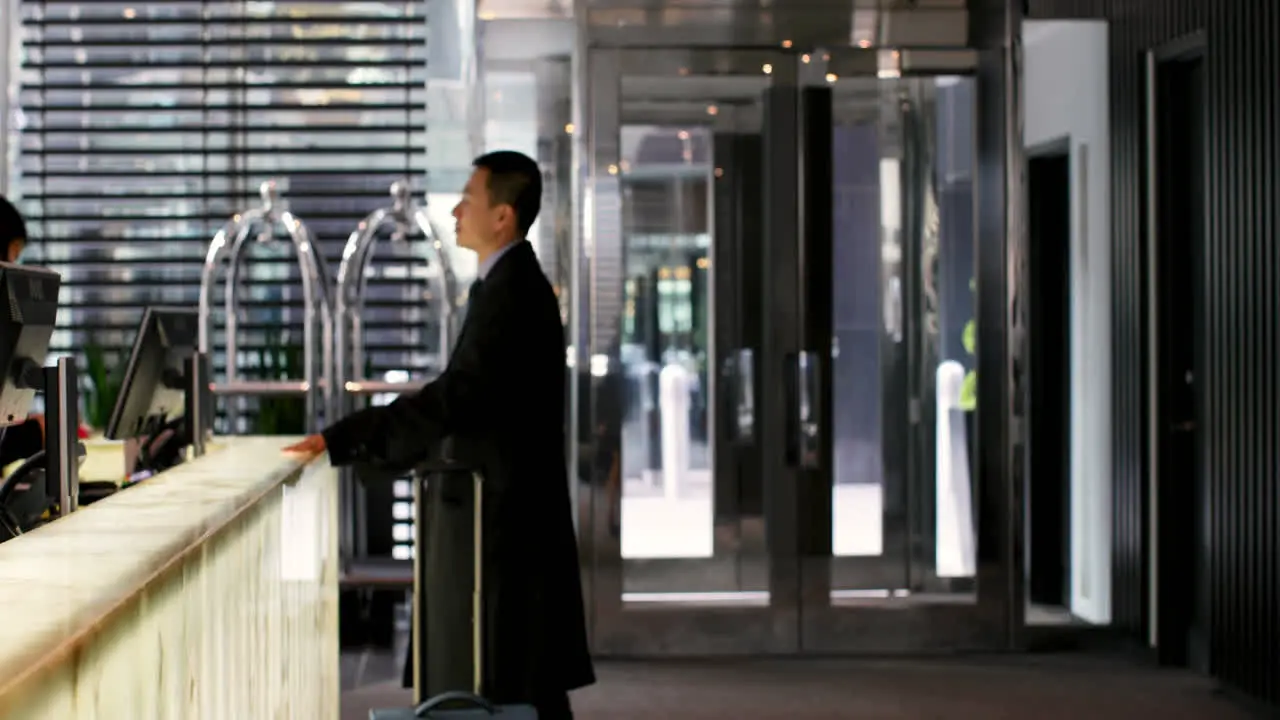 Side view of mixed race business people standing at reception in hotel 4k