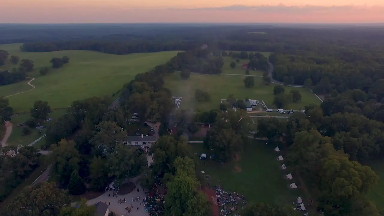 Fly over 4k Drone slow pull back of rural music and art festival on historic farm