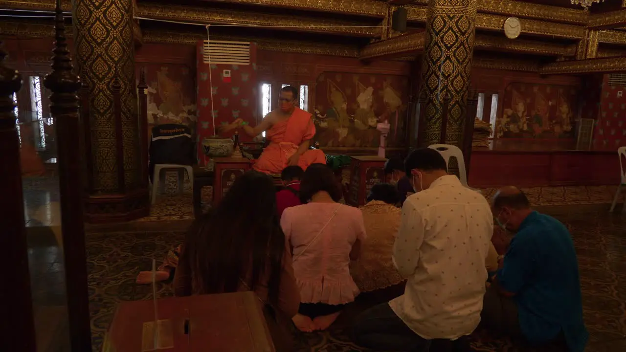 Buddhist monk blessing people by splashing water on their heads in Songkran ceremony Thailand