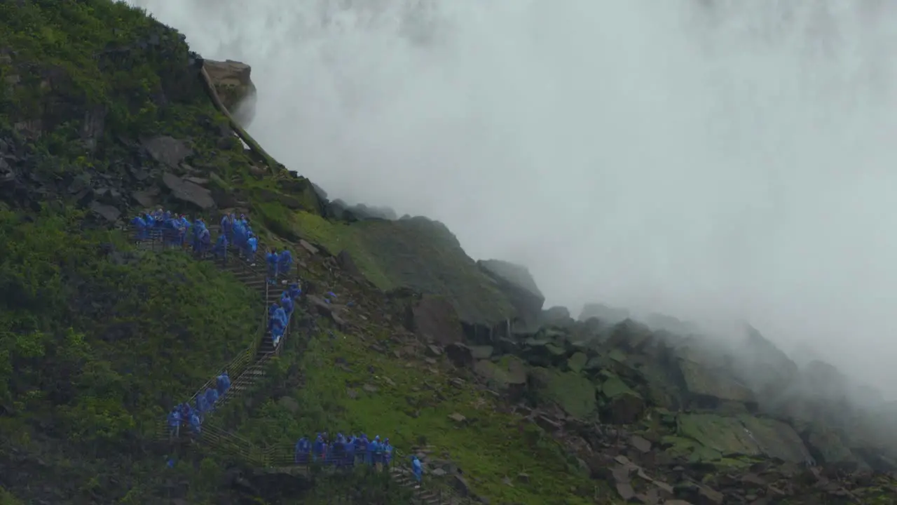 Queue of tourists with blue waterproof suits on side stairway at Niagara Falls