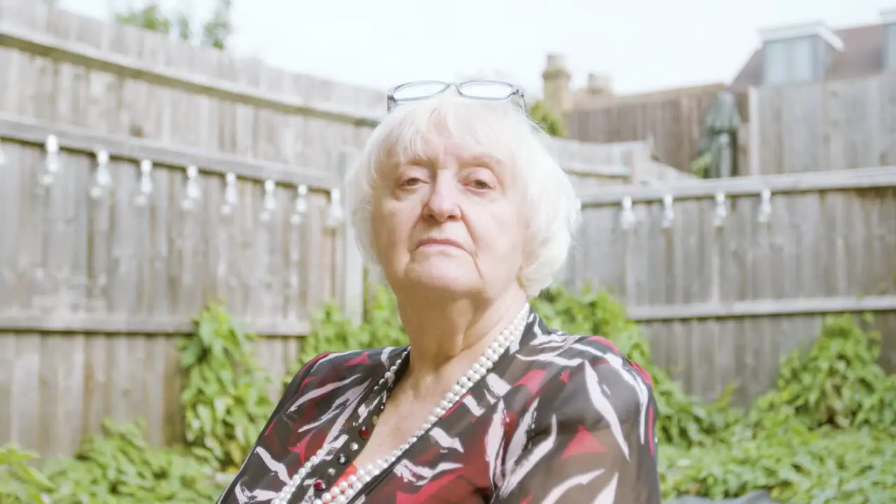 Elderly Woman looking down her nose at camera looking stern in her garden day