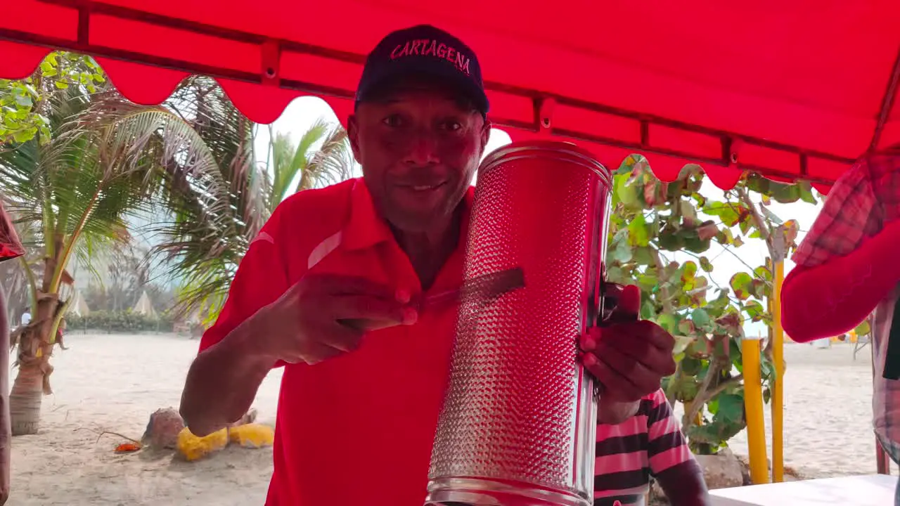 A man wearing a red shirt is playing an instrument called Guacharaca