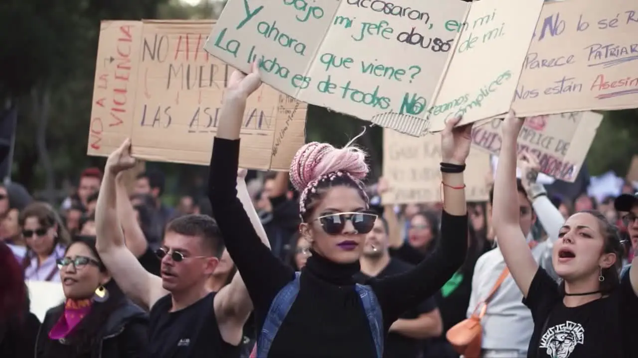 Women and men peacefully protesting marching and chanting songs against inequality marches in favor of women rights with messages written on boards