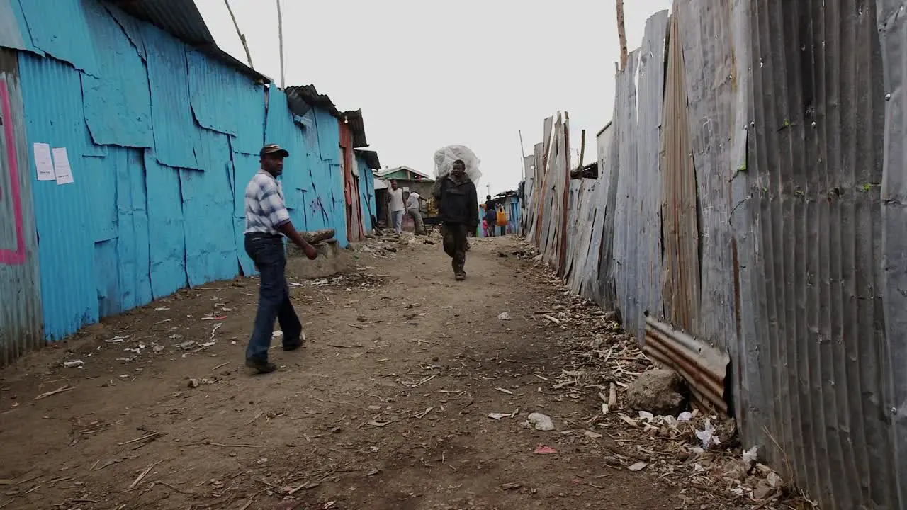 People walking on a narrow path in a slum