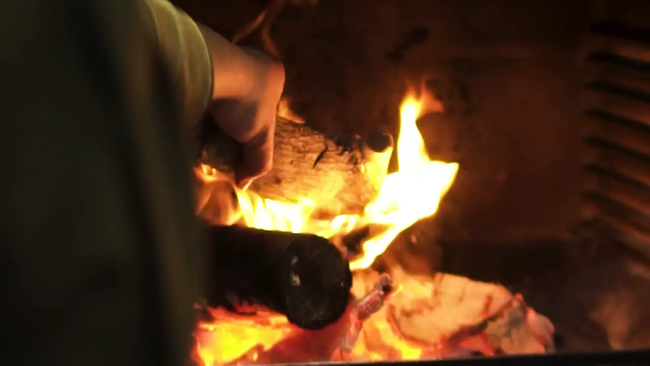 person throwing log of firewood into the fire