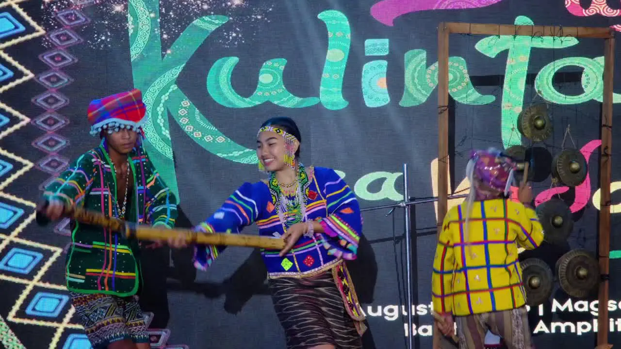 A group of stage performers wearing beautiful and colorful costumes on the stage with musical instruments