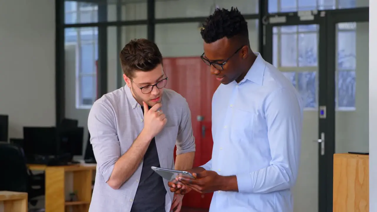 Front view of young mixed-race business team working on digital tablet in a modern office 4k