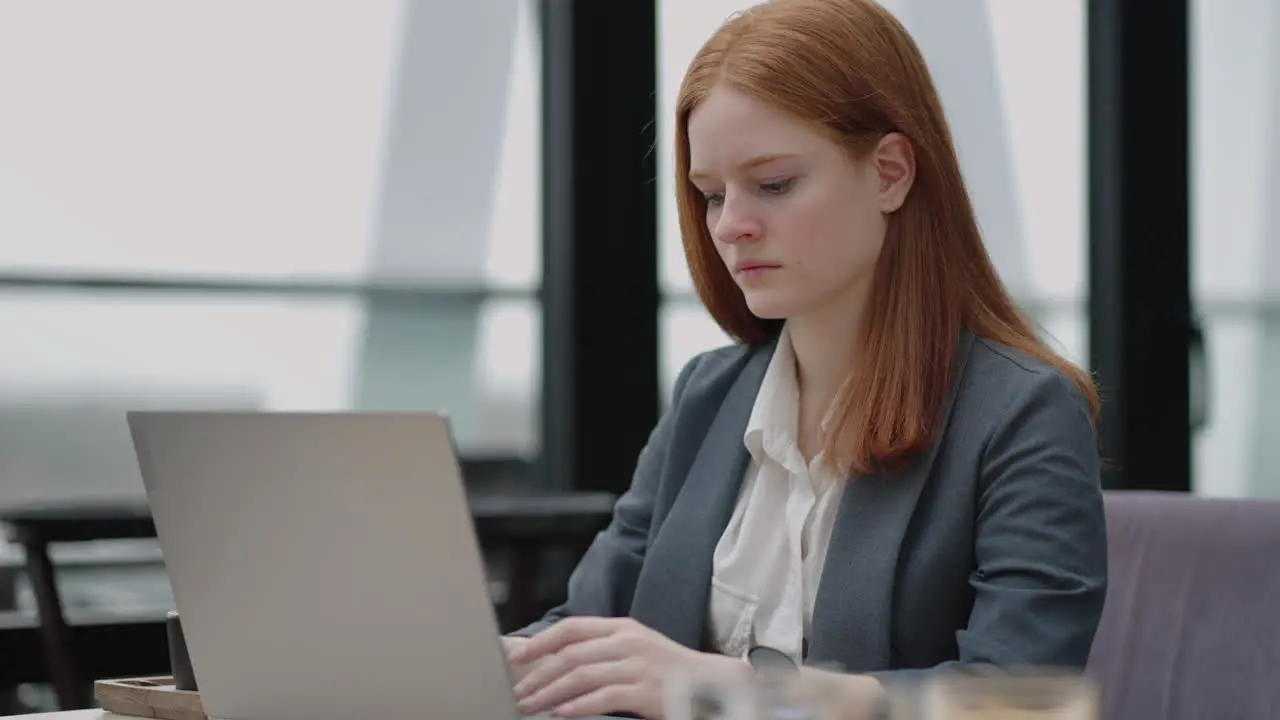 A young red-haired woman is working on a laptop Remote work Home office Office work A woman in a suit in the office is typing on a laptop