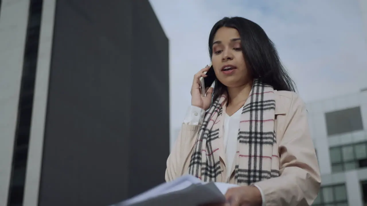 Businesswoman talking on smartphone on street Serious woman working with papers