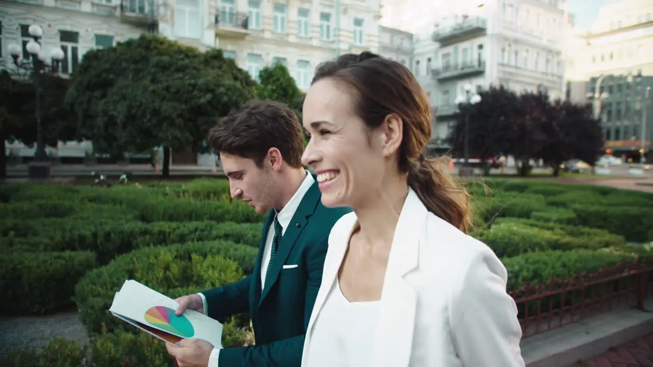 Excited business couple enjoying good statistics in paperwork on city street