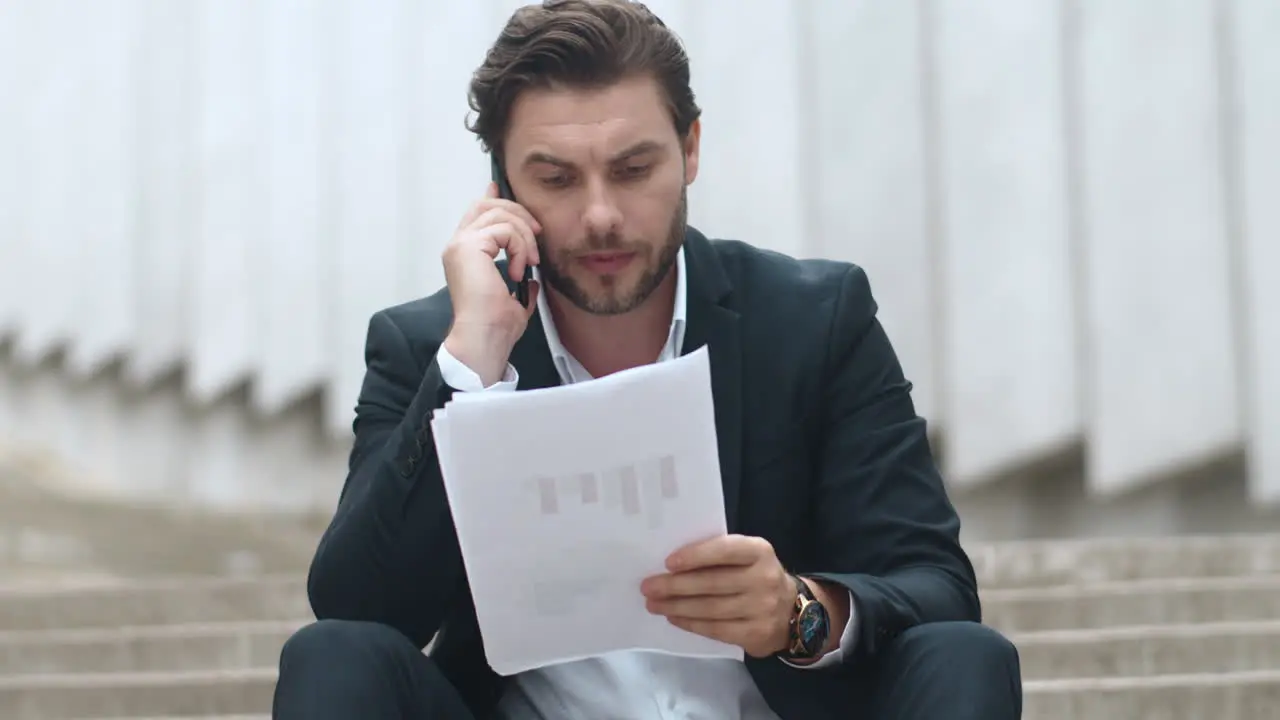 Businessman having conversation on cellphone at street Man sitting on stairs