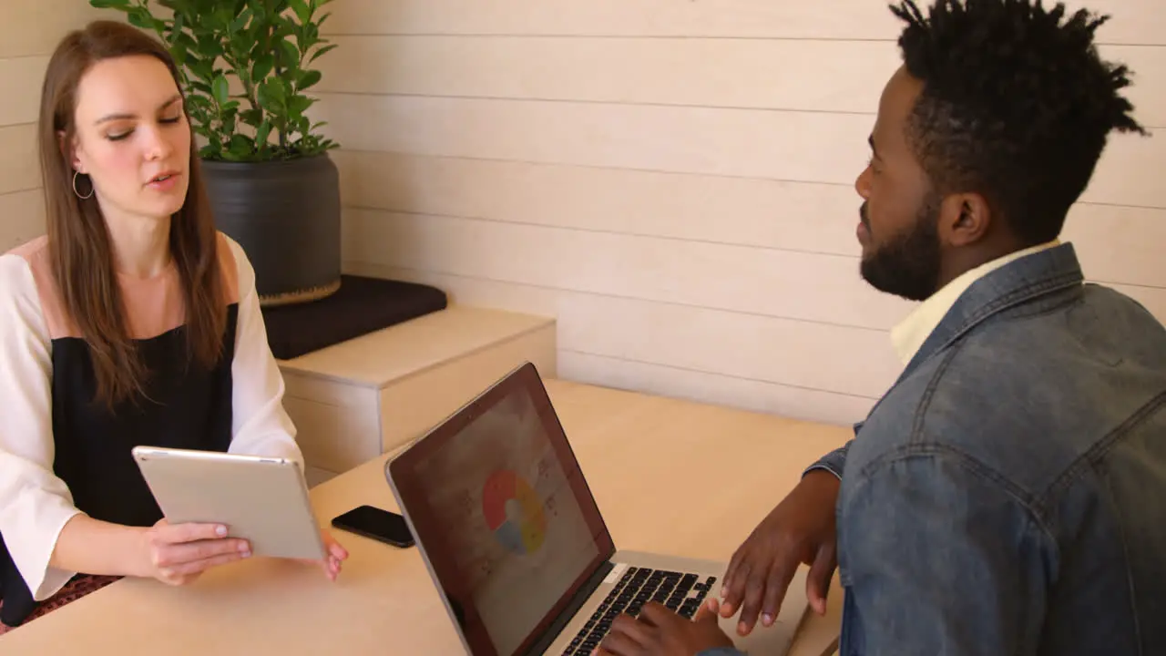 Young cool mixed-race business team planning and sitting with laptop at desk of modern office 4k