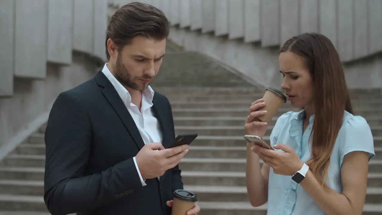 Entrepreneurs using smartphones on street Man and woman drinking coffee to go