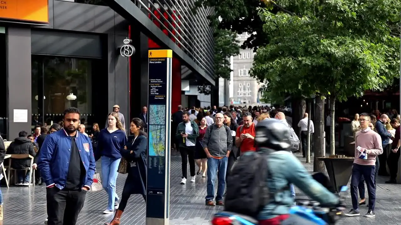 Slow motion of a group of people city pedestrians walking on a busy London street with Tower Bridge in the background