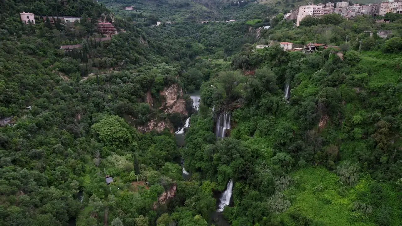 Cascading waterfalls in green forest Tivoli Italy Aerial toward