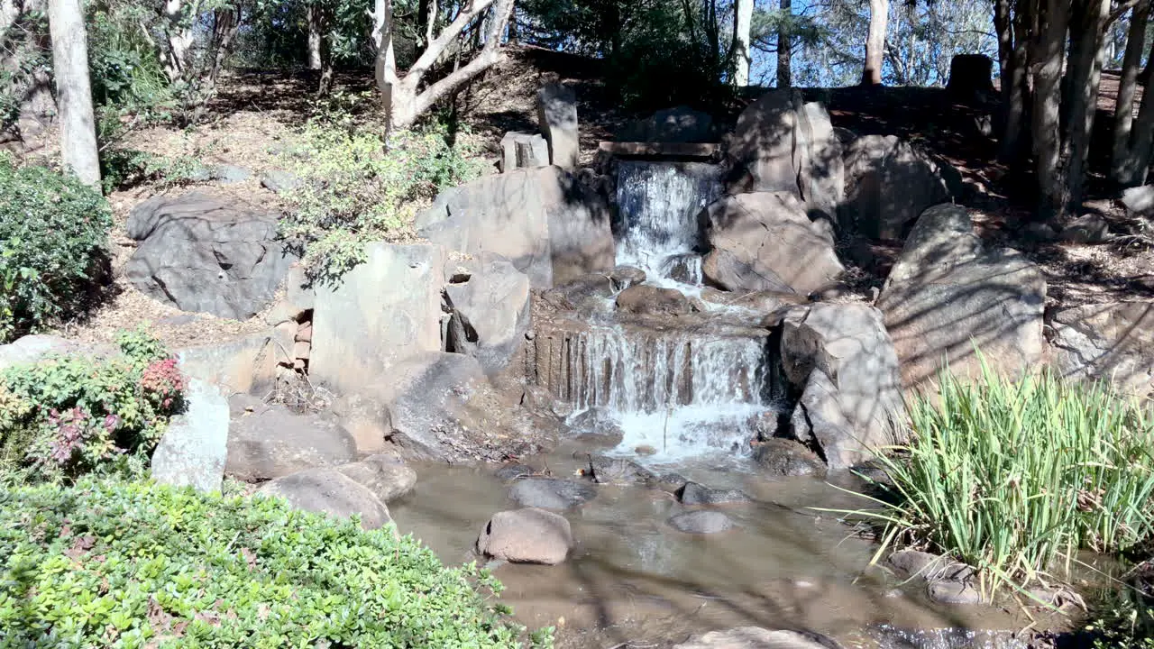 Slo-mo of waterfall surrounded by green foliage Ju Raku En Japanese Garden Toowoomba Australia