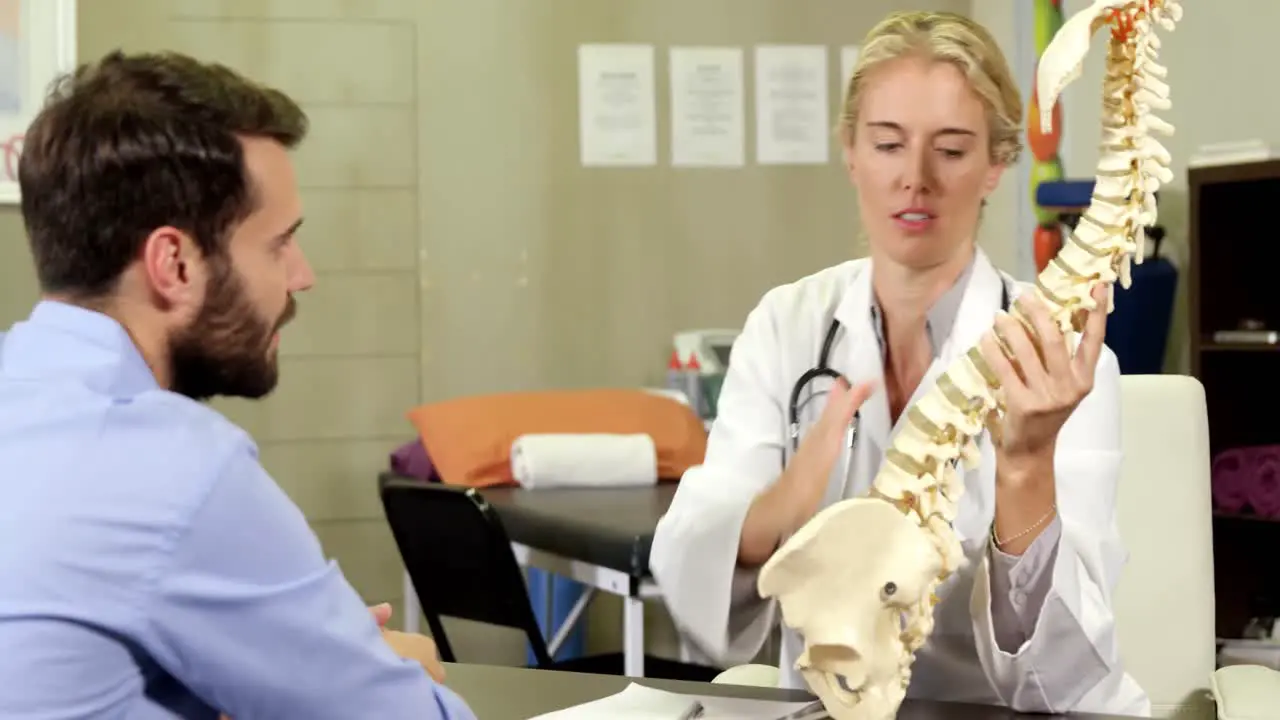 Physiotherapist explaining spine model to patient