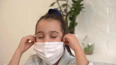 Little girl takes off her protective medical mask and smiles Stay home mom Coronavirus or COVID-19 Cute little girl in a protective mask