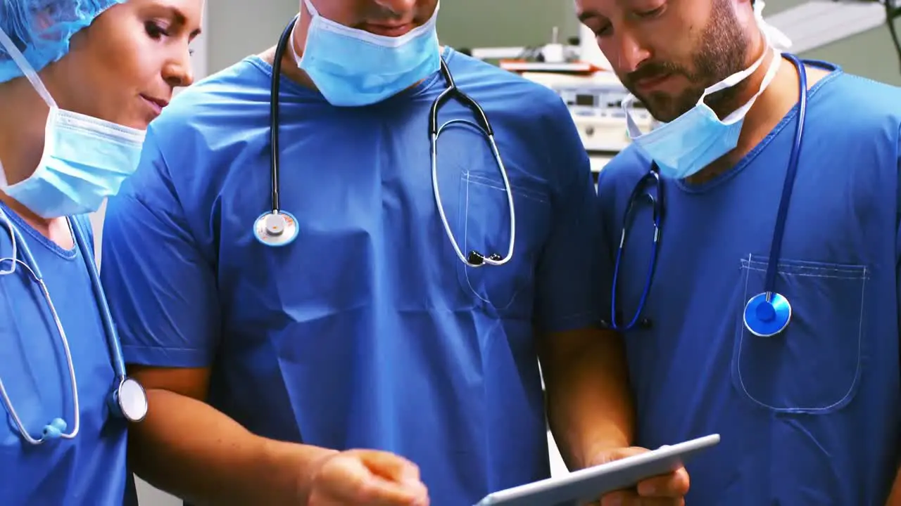 Male and female surgeons discussing over digital tablet in operation room