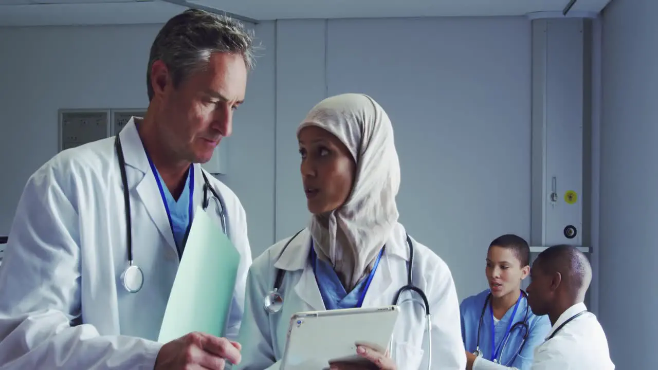 Front view of Multi-ethnic doctors discussing over digital tablet in hospital