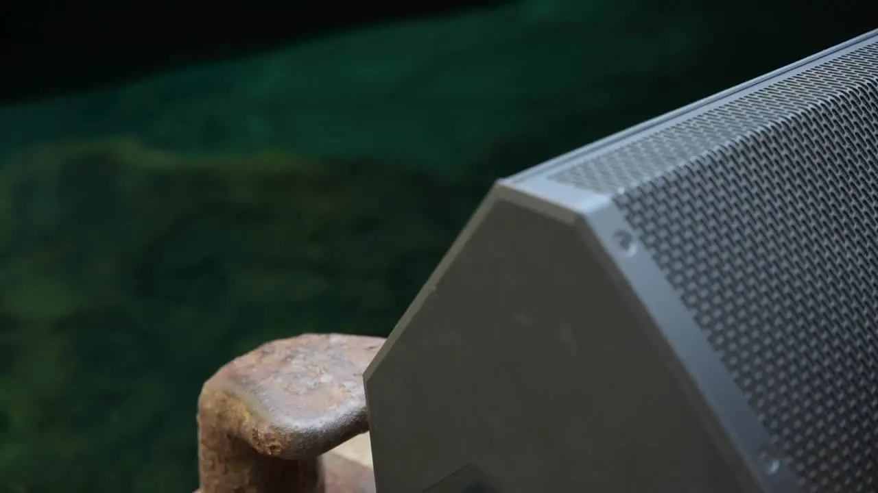 Grey speaker very close to the camera with water in the background