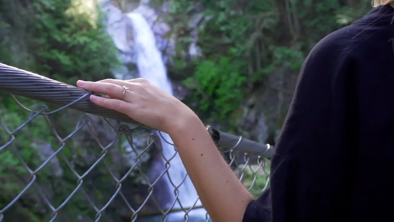 Woman crossing old traditional bridge in forest in British Columbia BC Canada with waterfall and river and hand