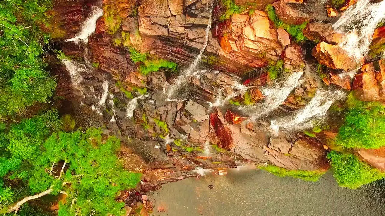 Birds eye aerial shot flying up over a cliff with water streaming down