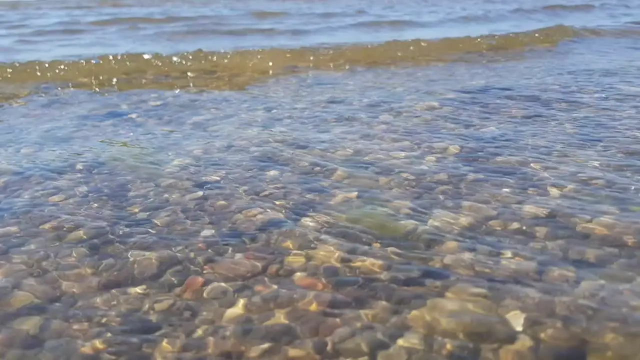 Baltic sea small waves come in transparent water we can see small pebble rock in bottom