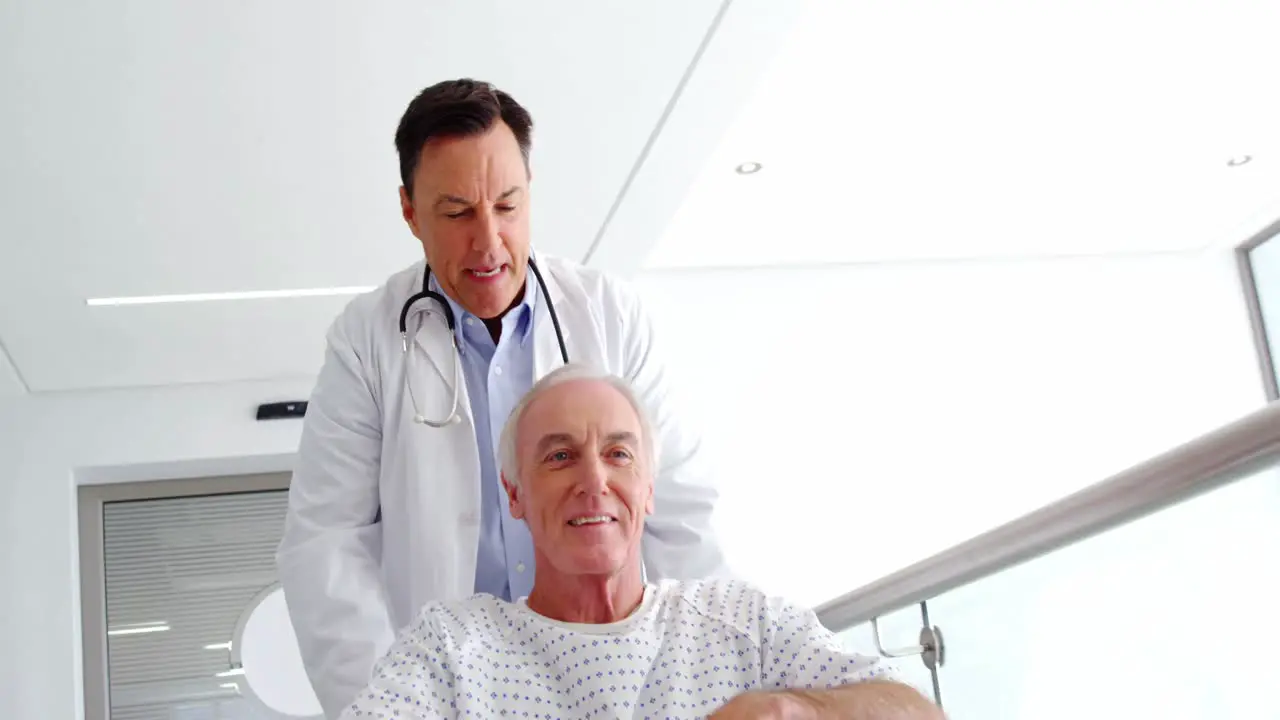 Doctor holding senior patient on wheelchair in passageway