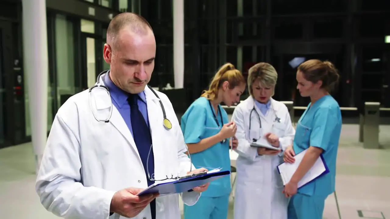 Doctor looking at clipboard in hospital corridor