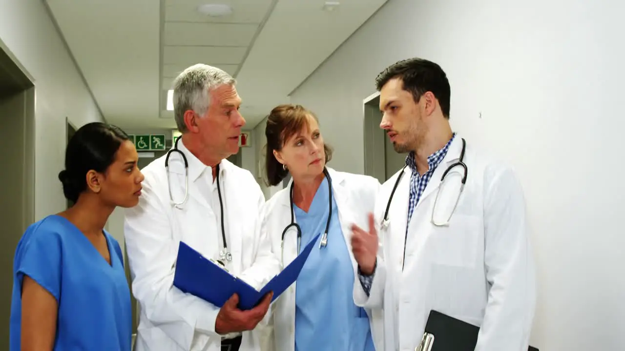 Doctors and nurse discussing over medical report while walking in corridor