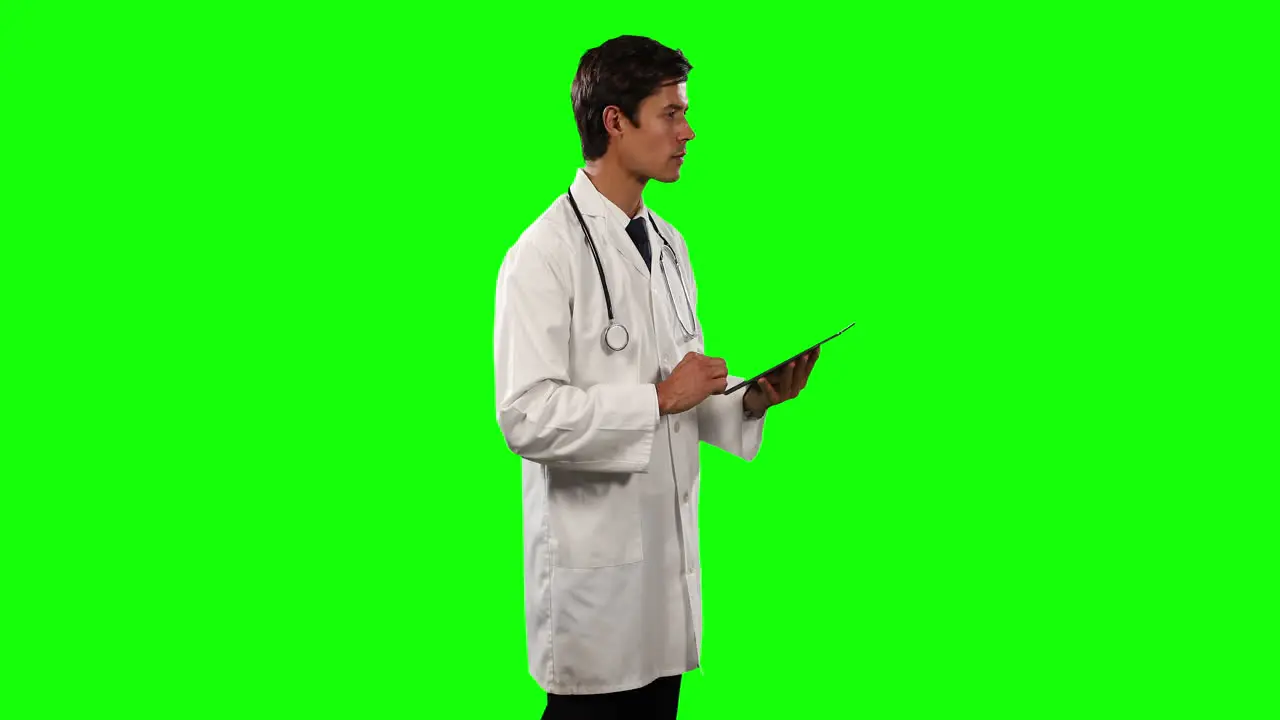 Side view of a doctor using his digital tablet with green screen