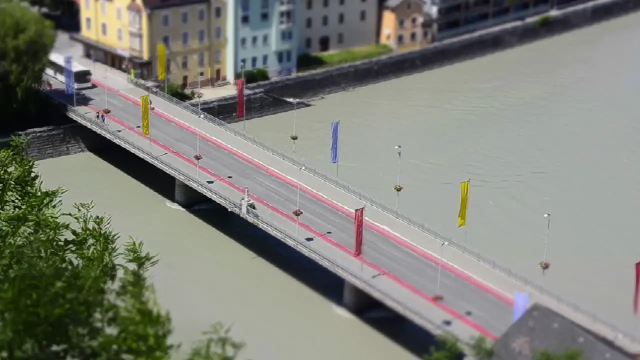 Miniature scene of a timelapse of a bridge over a river with buses and cars driving over it in a small city