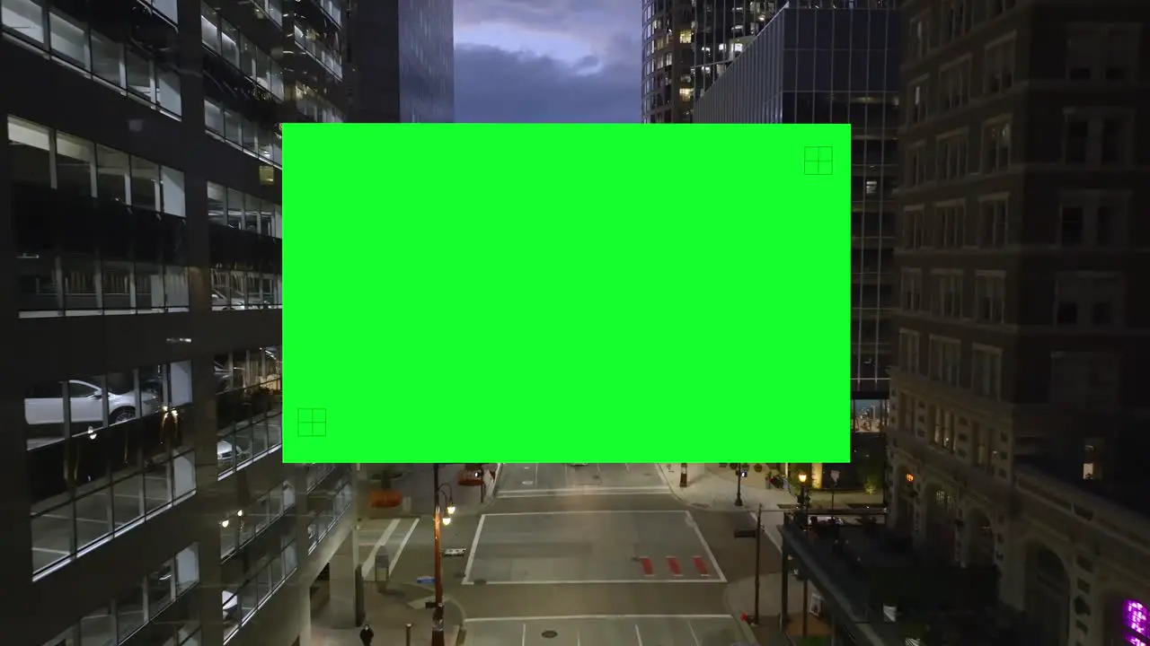 Drone shot of a Green Screen filling the frame inside a illuminated city Chroma Key