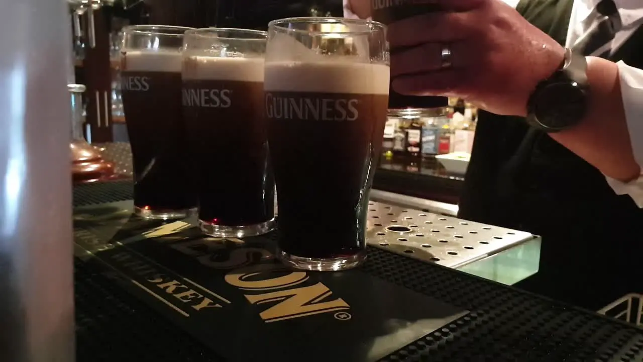 Unseen bartender serving pints of Guinness in a Bar