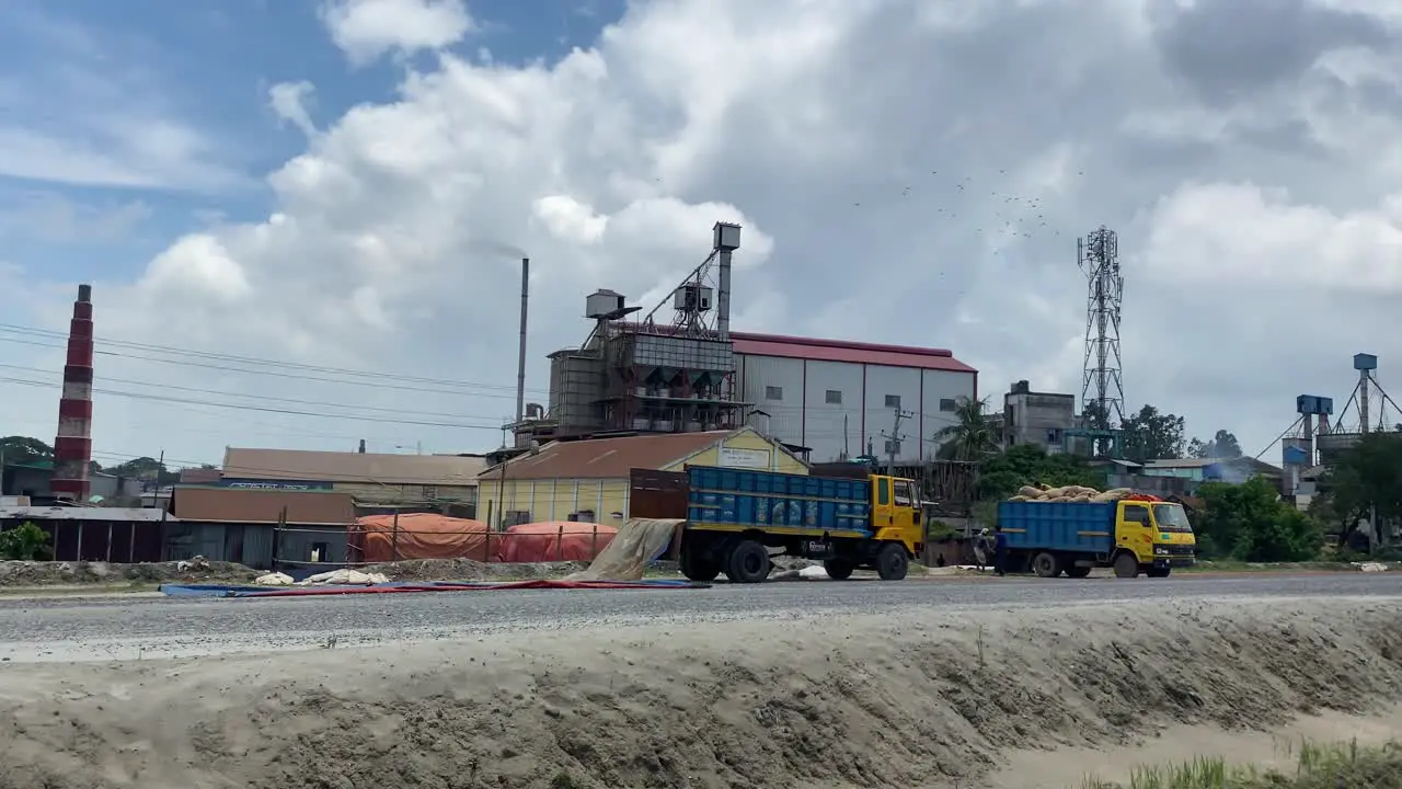 Industrial factory with chimney and parked machines drive by view