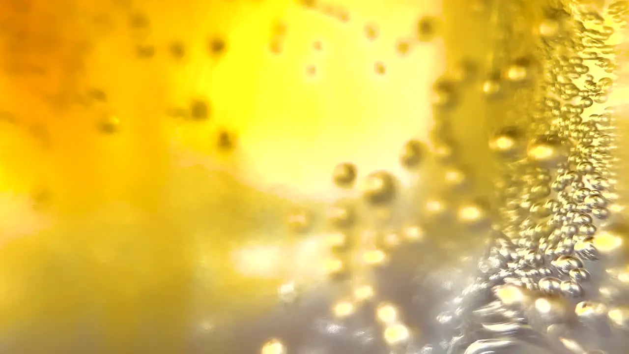 Macro Coffee With Tonic Soda Sparkling Air Bubbles Rising in a Glass of Bright Yellow-Golden Fluid Liquid